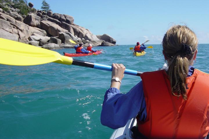 people kayaking along rocks