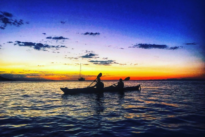 kayak and boat during sunset in the water